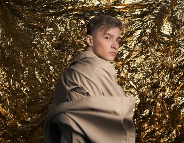 Bej ceketli, altın kaplama beyaz gömlekli şık bir adam..