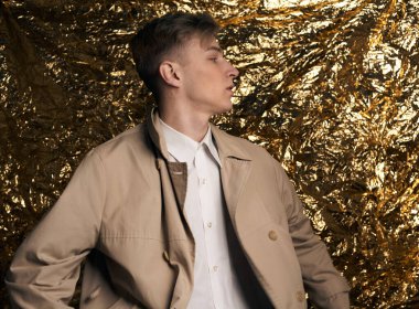 Bej ceketli, altın kaplama beyaz gömlekli şık bir adam..