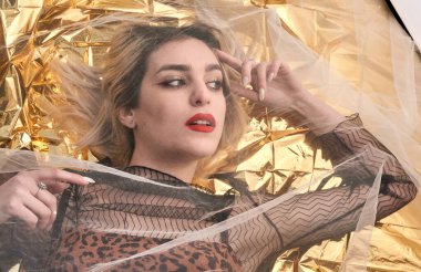 Altın folyoda, tül kumaşın altında güzel bir kız..