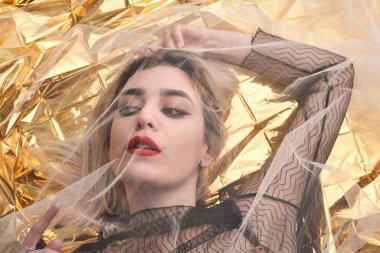 Altın folyoda, tül kumaşın altında güzel bir kız..