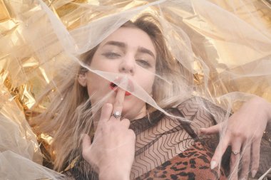 Altın folyoda, tül kumaşın altında güzel bir kız..