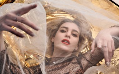 Altın folyoda, tül kumaşın altında güzel bir kız..