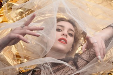 Altın folyoda, tül kumaşın altında güzel bir kız..