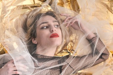 Altın folyoda, tül kumaşın altında güzel bir kız..