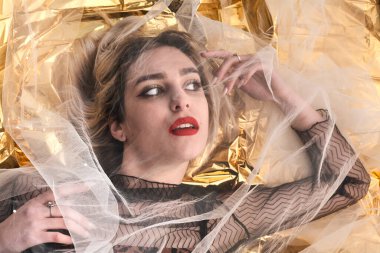 Altın folyoda, tül kumaşın altında güzel bir kız..