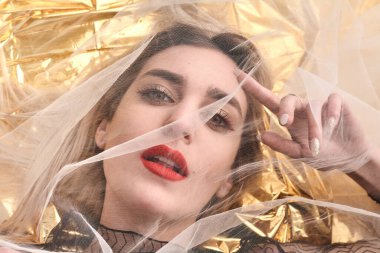 Altın folyoda, tül kumaşın altında güzel bir kız..