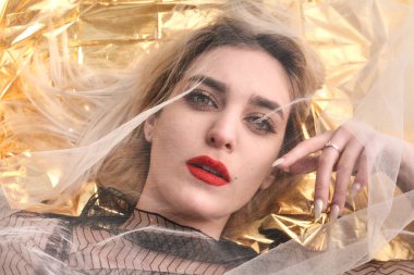 Altın folyoda, tül kumaşın altında güzel bir kız..