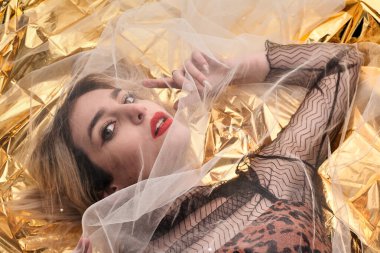 Altın folyoda, tül kumaşın altında güzel bir kız..