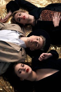 Altın bir arka planda uzanan şık genç insanlar.