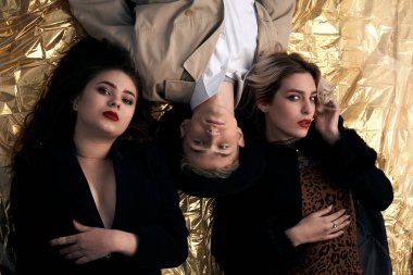 Altın bir arka planda uzanan şık genç insanlar.