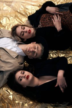 Altın bir arka planda uzanan şık genç insanlar.