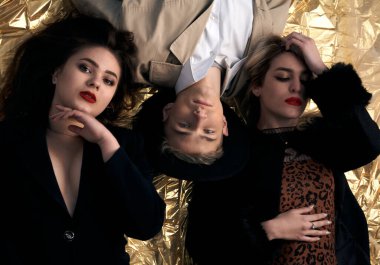 Altın bir arka planda uzanan şık genç insanlar.