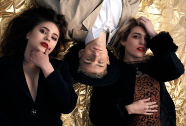 Altın bir arka planda uzanan şık genç insanlar.