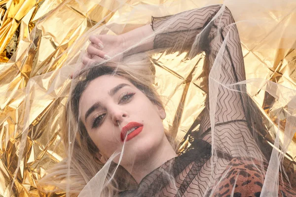 Altın folyoda, tül kumaşın altında güzel bir kız..