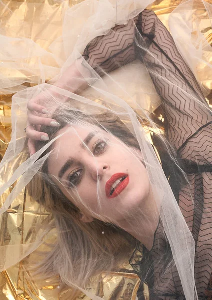 Altın folyoda, tül kumaşın altında güzel bir kız..