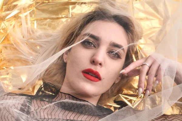 Altın folyoda, tül kumaşın altında güzel bir kız..
