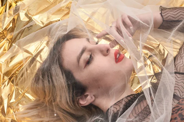Altın folyoda, tül kumaşın altında güzel bir kız..