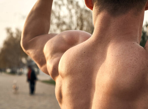 Muscular fitness model posing on the promenade on a sunny day.