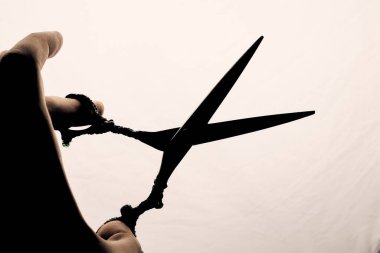 Hafif bir arka planda kuaför siluetinin elinde makas var..