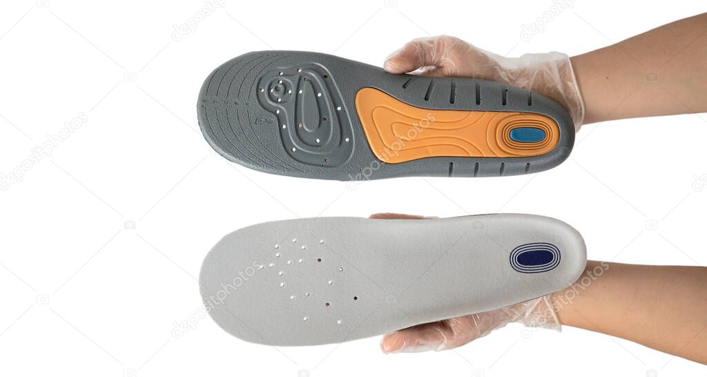 Orthopedist holds the insoles in his hands on white background, close-up. Only hands , on hygienic gloves.