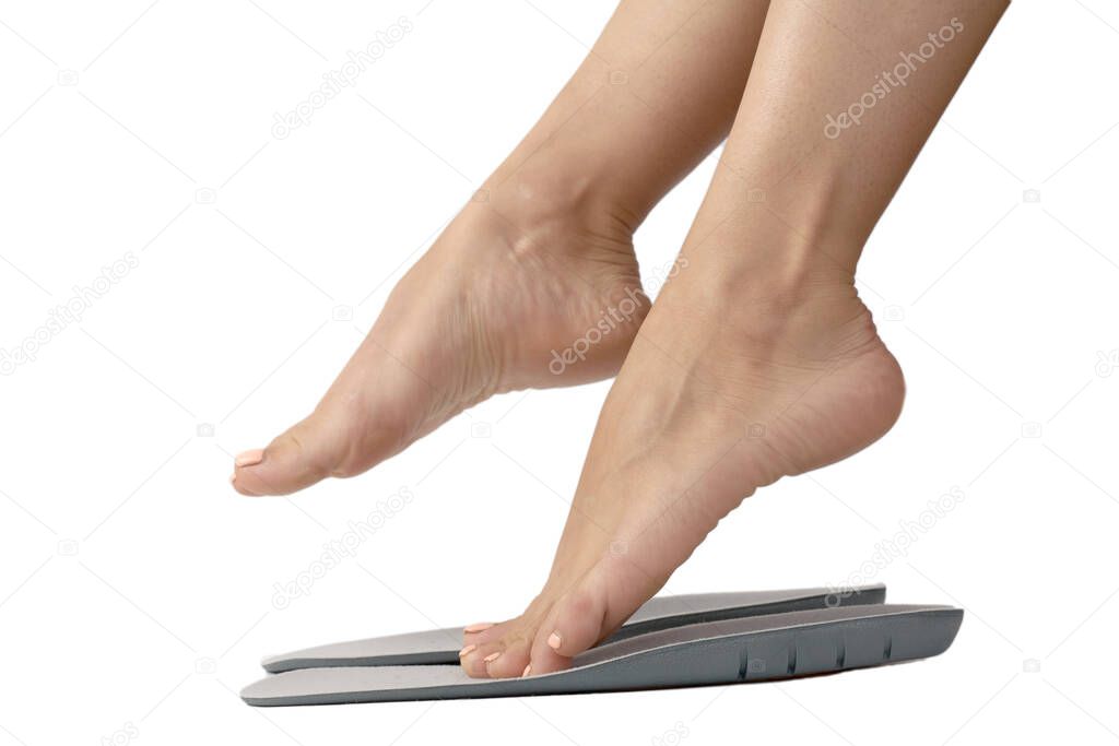 Beautiful female feets and insoles isolated on a white background. The girl tries on orthopedic insoles.