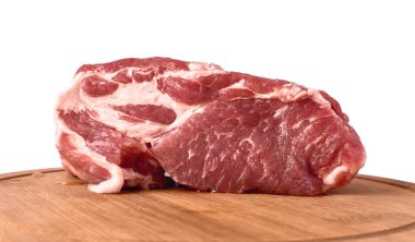 Beyaz arka planda tamamen çiğ domuz eti var. Tahta bir tahtanın üzerinde basit bir et kompozisyonu. Yan görünüm ve tahtadaki boşluk.