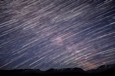 Yıldızlı gökyüzü güzel gece Panoraması göktaşları ve karlı dağlar çerçevede dairesel parça şeklinde yıldız izleri ile