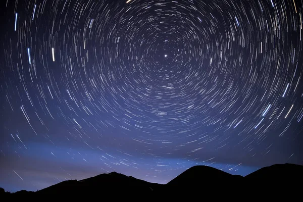 円形のトラックと山の背景の夜空に輝きの形で 北極星の周りの回転星の明るいトレース — ストック写真