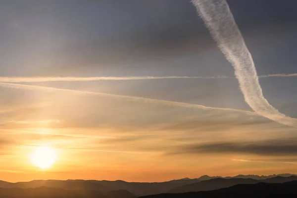 空と雲とハローで航空機の痕跡と山の美しい日の出 — ストック写真