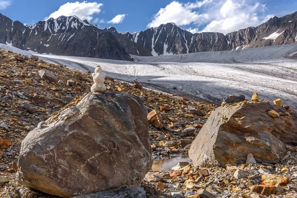 Bir taş yüksek dağlarda bir buzul, dağ zirveleri ve mavi gökyüzü yaz aylarında zemin karşı küçük bir kardan adam
