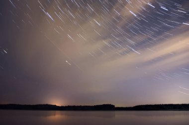 Bir orman ile gece manzarası inanılmaz yumuşak su Nehri, bulutlar ve yıldız koyu mavi gökyüzü raylara şeklinde yansıması