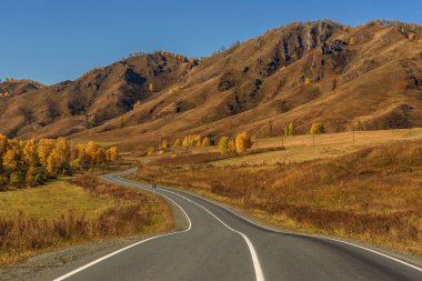 Altın arka plan mavi gökyüzünün kenarında ağaçta ormanıyla kaplı dağlarında asfalt yol
