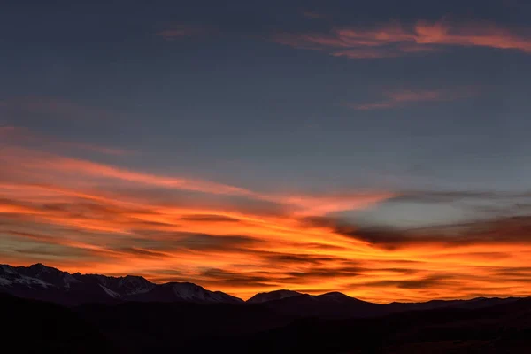 夕日に雪で覆われた山脈の驚くほどの青い空にピンクと燃えるような巻雲とビュー — ストック写真
