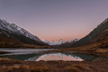 Sonbaharda bir buzul ve karlı dağlar ve yumuşak su yansımaları Gölü nün muhteşem pembe gündoğumu