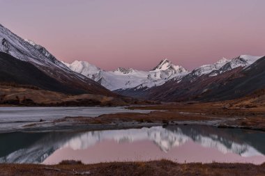 Sonbaharda bir buzul ve karlı dağlar ve yumuşak su yansımaları Gölü nün muhteşem pembe gündoğumu
