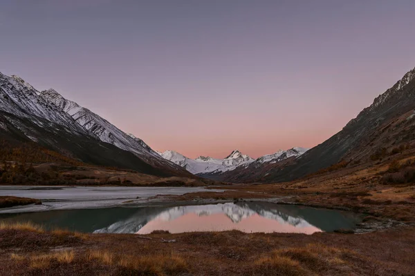 Sonbaharda bir buzul ve karlı dağlar ve yumuşak su yansımaları Gölü nün muhteşem pembe gündoğumu