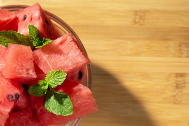 Nane yaprakları ile cam kase üzerinde karpuz parçaları, ahşap tahta