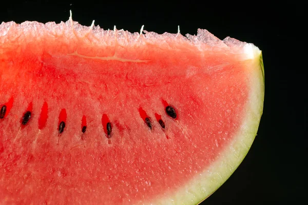 slice of watermelon with seeds on black background