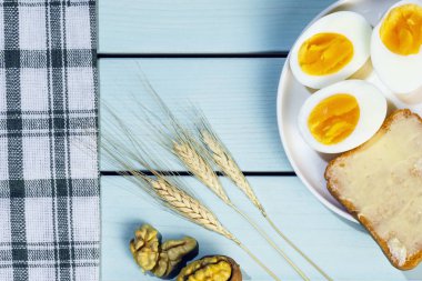 Yumurta ile sabah kahvaltısı, mavi ahşap masada tereyağı ve ceviz ile kavrulmuş ekmek, üst görünüm görüntüsü