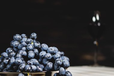 kırmızı üzümler ve soluk şarap kadehleri koyu arkaplanda, kopyalama alanı