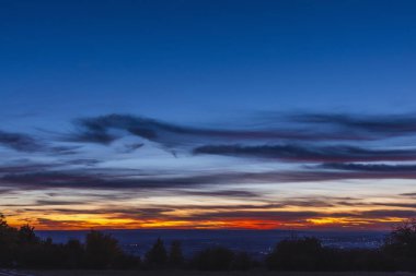 Şehrin üzerinde gün batımı, fotokopi alanı ile alacakaranlık manzarası, turuncu bulutlar