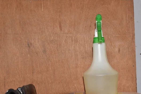 Su püskürtücü kahverengi arkaplanda izole edilmiş. Suyla doldurulmuş küçük plastik beyaz ve yeşil renk spreyi..
