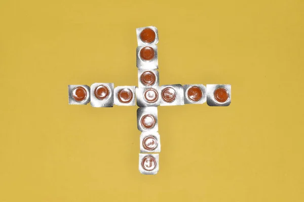 Öksürük ağrısı çeken boğaz pastil renkli haplar arka plan sarısı ve tıbbi sembol.