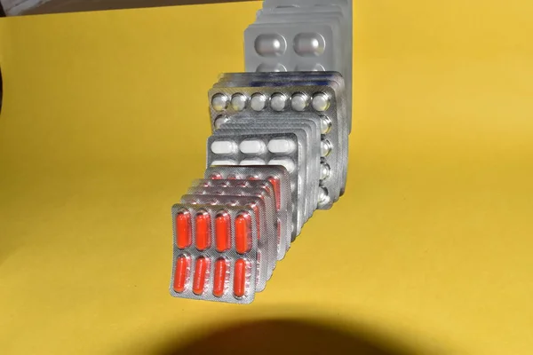 Farklı renkte haplar ve kapsüller. Kabarcıklar. İlaç olarak kullanılmak üzere ilaç olarak kullanılıyor. Sarı arka planda izole edilmiş.