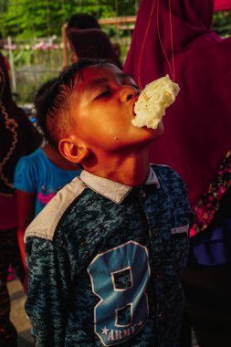 Jakarta, Endonezya - 17 Ağustos 2018: Küçük çocuk Endonezya'nın bağımsızlık günü kutlamalarında kraker yiyen yarışı takip ediyor