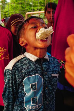 Jakarta, Endonezya - 17 Ağustos 2018: Küçük çocuk Endonezya'nın bağımsızlık günü kutlamalarında kraker yiyen yarışı takip ediyor