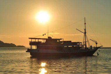 Tropikal Komodo adasında sakin bir demirleme de bir yelkenli arkasında batan güneş, Labuan Bajo, Fores, Endonezya