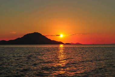 Turuncu gökyüzü ve deniz dalgaları arka plan ile Amazing gün batımı. Tropik Komodo adasında Güzel Gün Batımı, Labuan Bajo, Fores, Endonezya