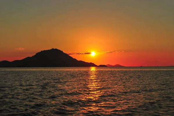 Turuncu gökyüzü ve deniz dalgaları arka plan ile Amazing gün batımı. Tropik Komodo adasında Güzel Gün Batımı, Labuan Bajo, Fores, Endonezya