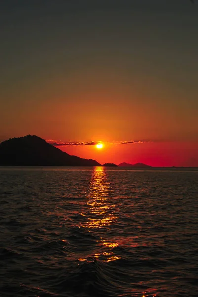 Pôr-do-sol incrível com céu laranja e fundo ondas do mar. Belo pôr do sol na ilha tropical de Komodo, Labuan Bajo, Fores, Indonésia — Fotografia de Stock